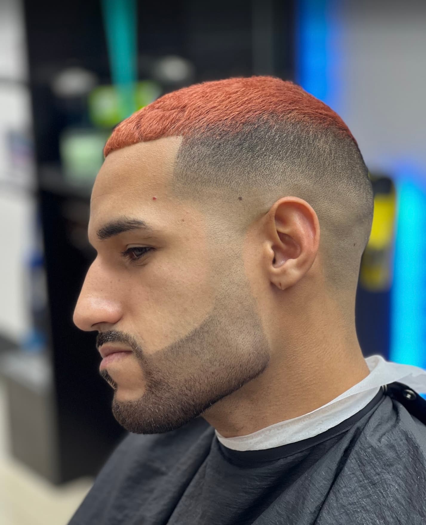 Perfil con high fade, barba delineada y cabello teñido en cobre